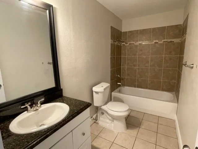 Bathroom featuring a white vanity with an undermount sink, dark countertop, and a framed mirror