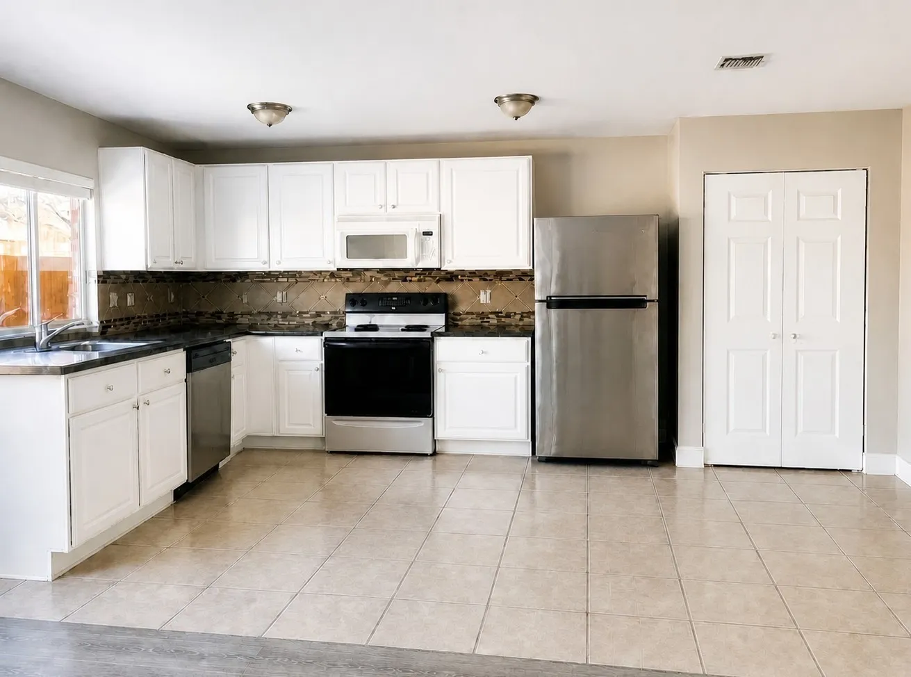 Kitchen featuring white cabinetry, stainless steel appliances, a tiled backsplash, and tiled flooring