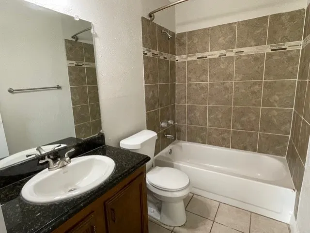 Bathroom featuring a white vanity with a dark granite-finish countertop, an undermount sink, and a chrome-finish faucet