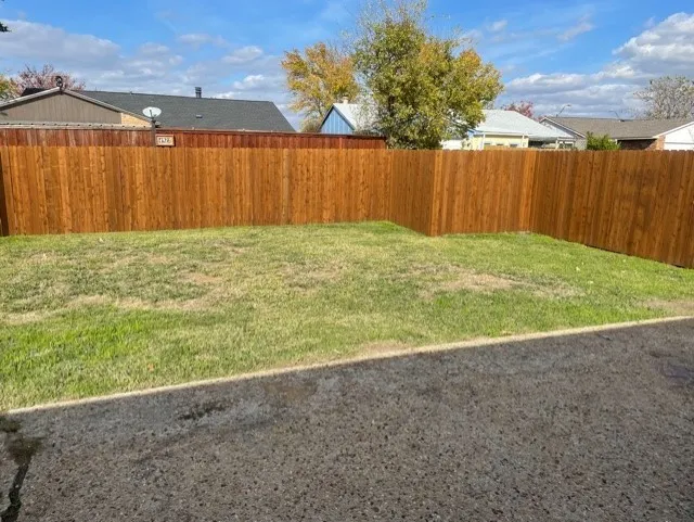 Expansive grassy yard area with perimeter wood fencing