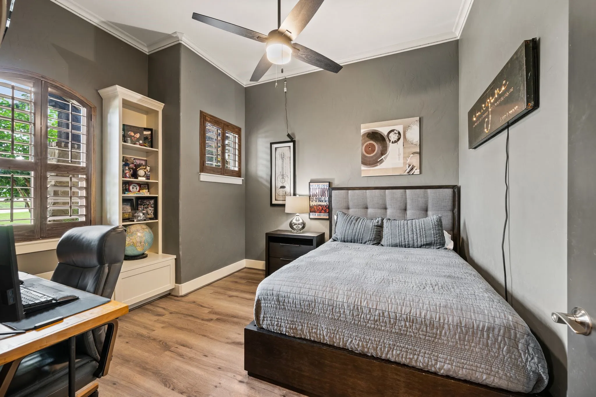 This inviting secondary bedroom features built-in display cabinetry and plantation shutters!