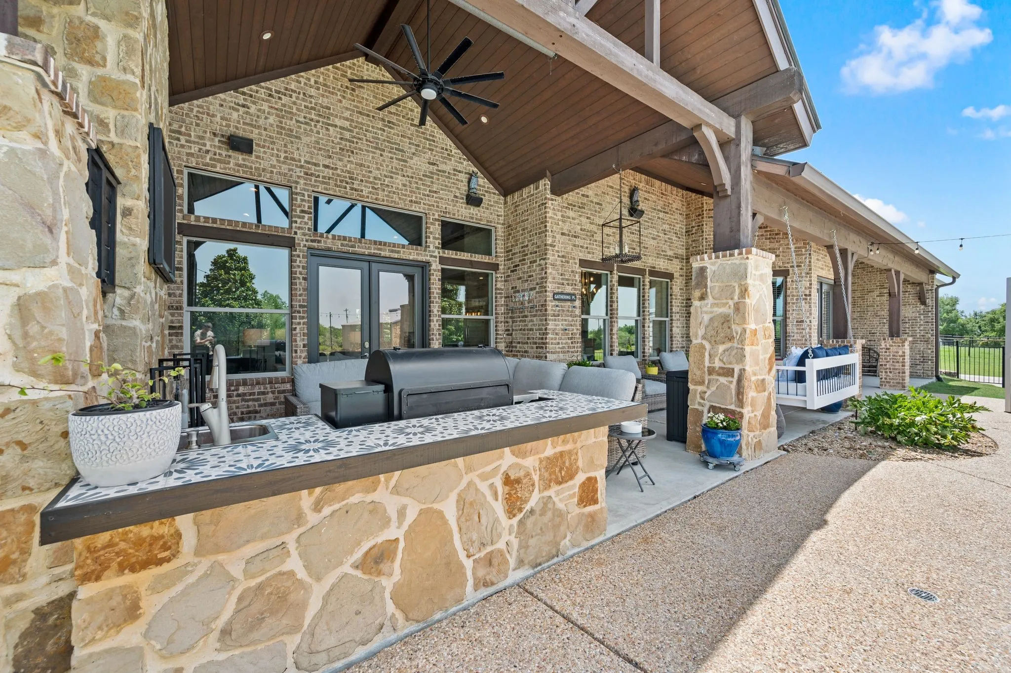 The impressive outdoor kitchen features room for a grill, a sink, generous counter space & a soaring covered patio with ceiling fan and fireplace!