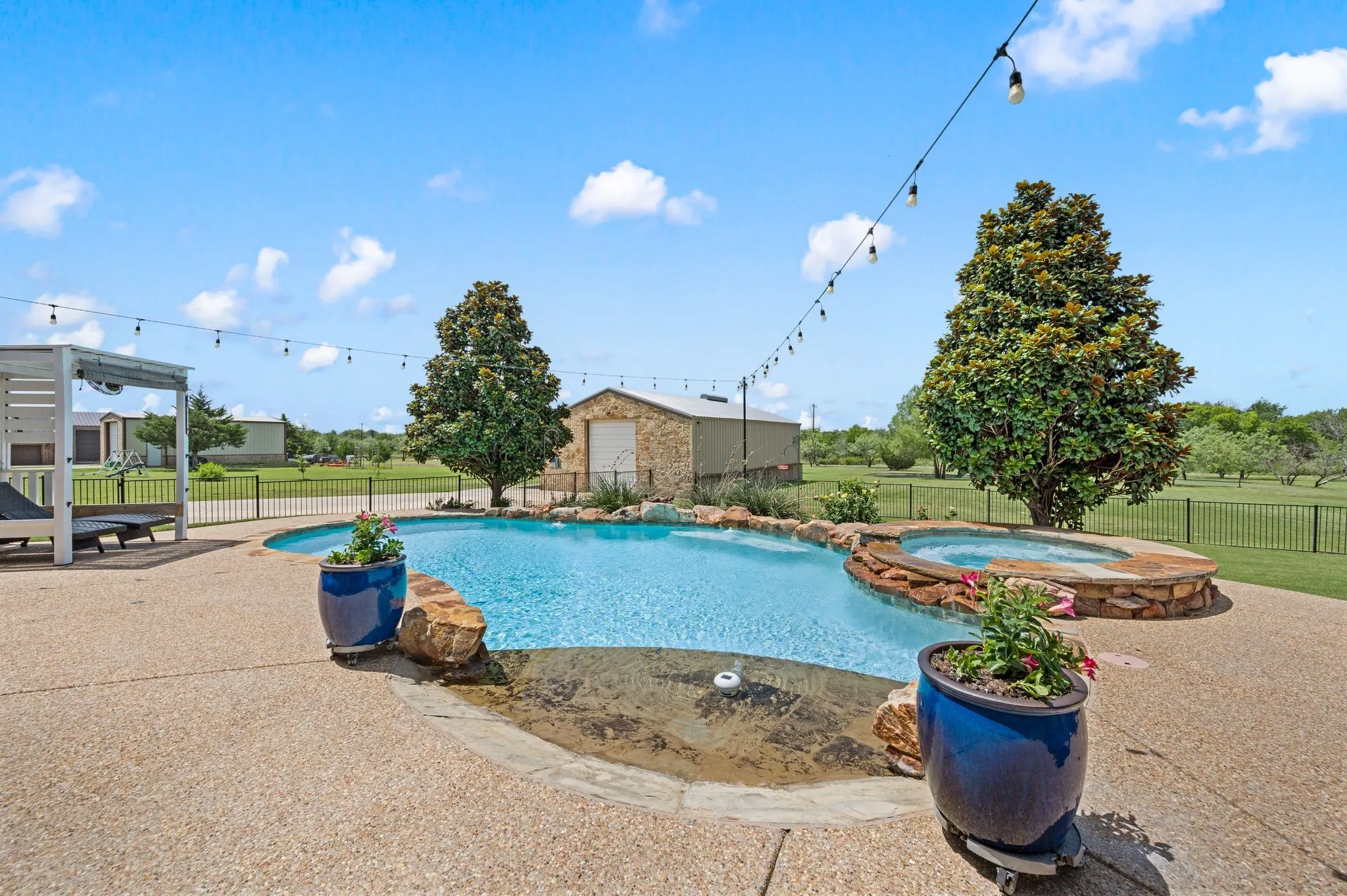 A sparkling resort-style pool with attached spa, stone accents & surrounding patio creates the perfect backyard escape.