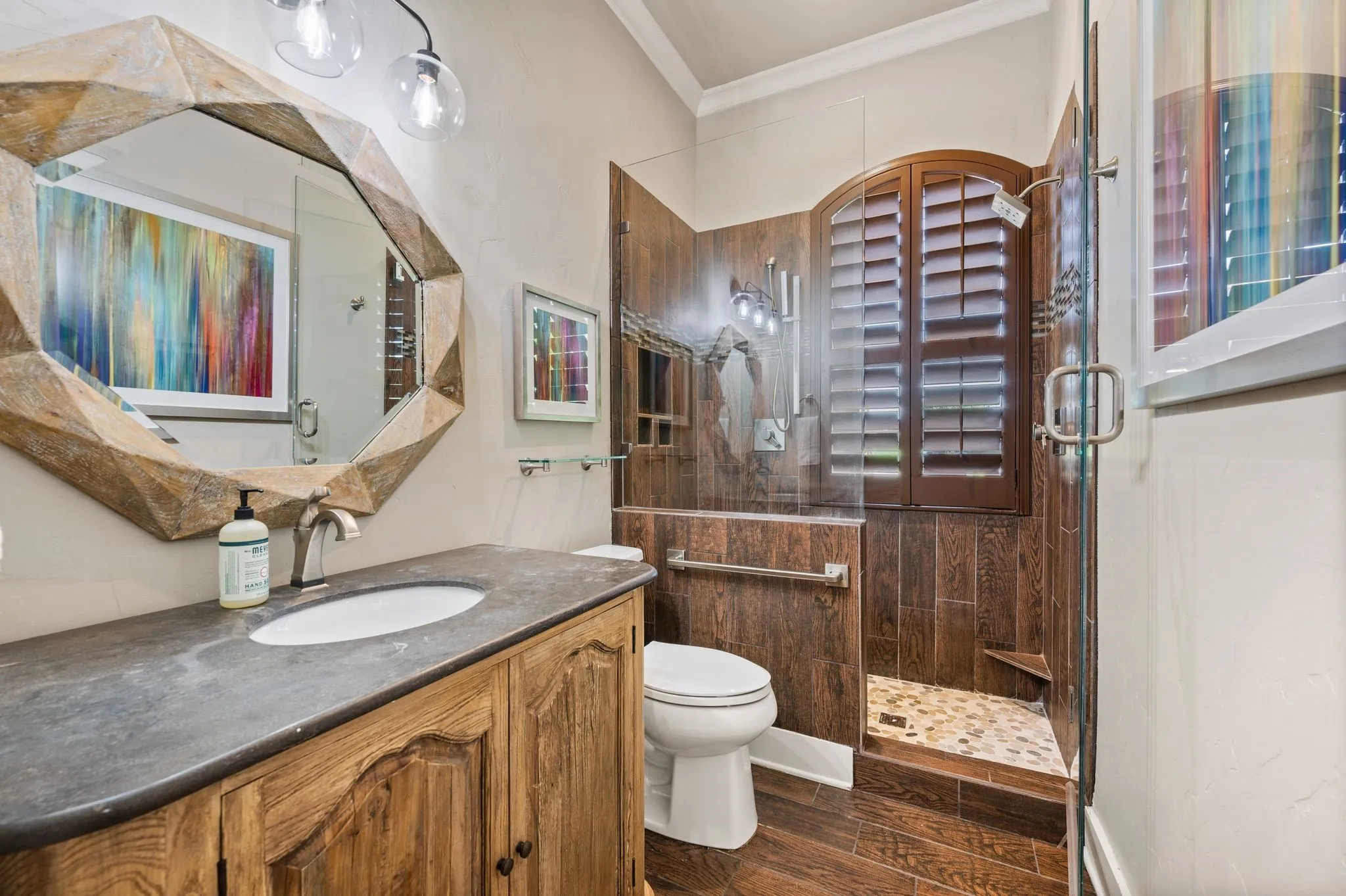A beautifully finished bathroom offers a rustic vanity, glass-enclosed walk-in shower and wood like tile!