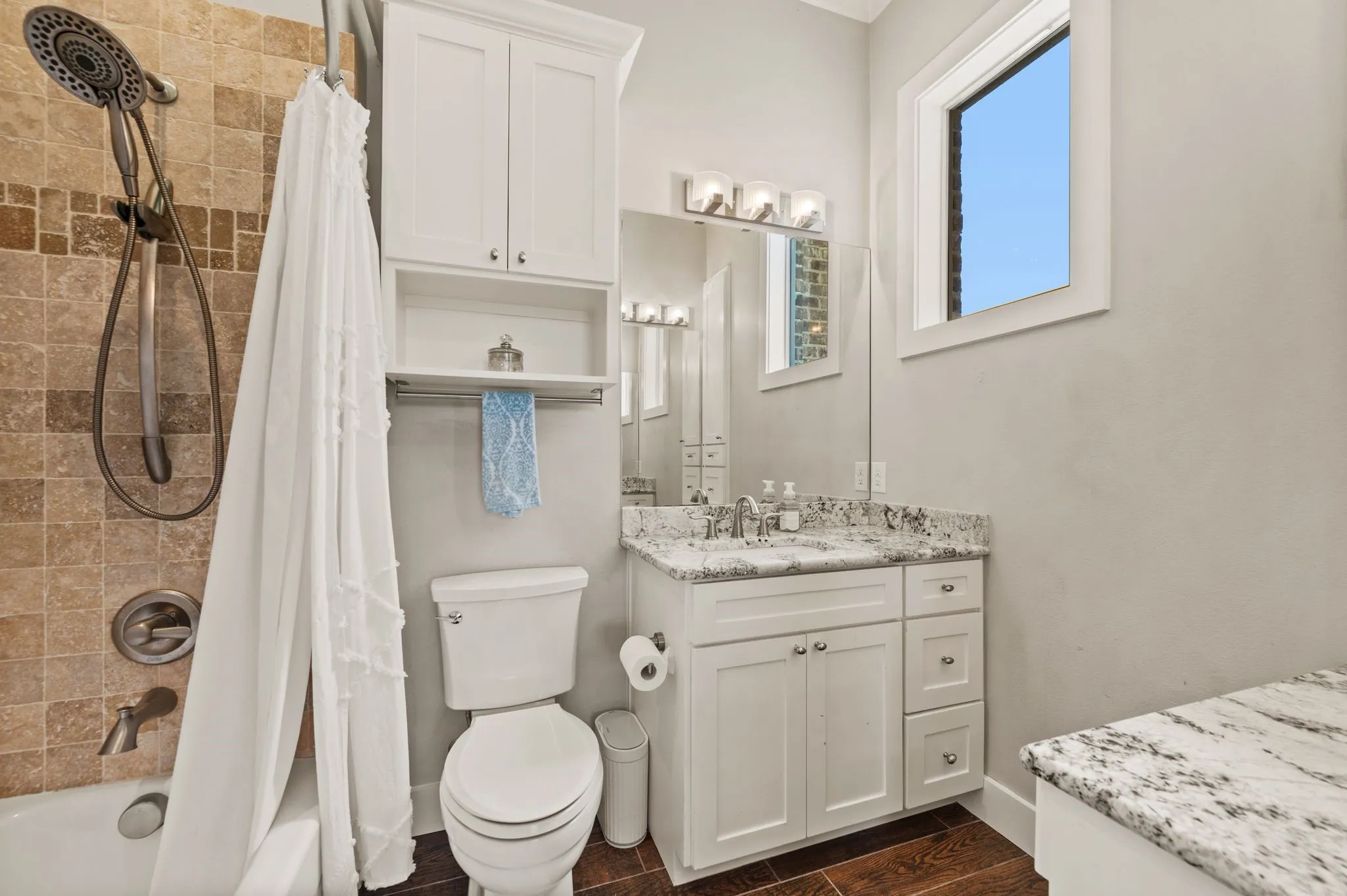 The private ensuite bathroom features a granite-topped vanity, generous storage & a tiled tub and shower combination.