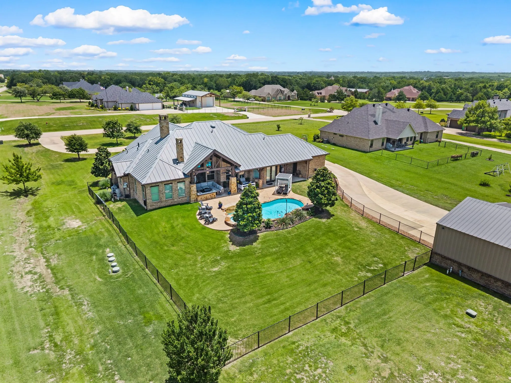 This view showcases the fenced backyard, sparkling pool, covered outdoor living areas & generous lawn surrounding the home.