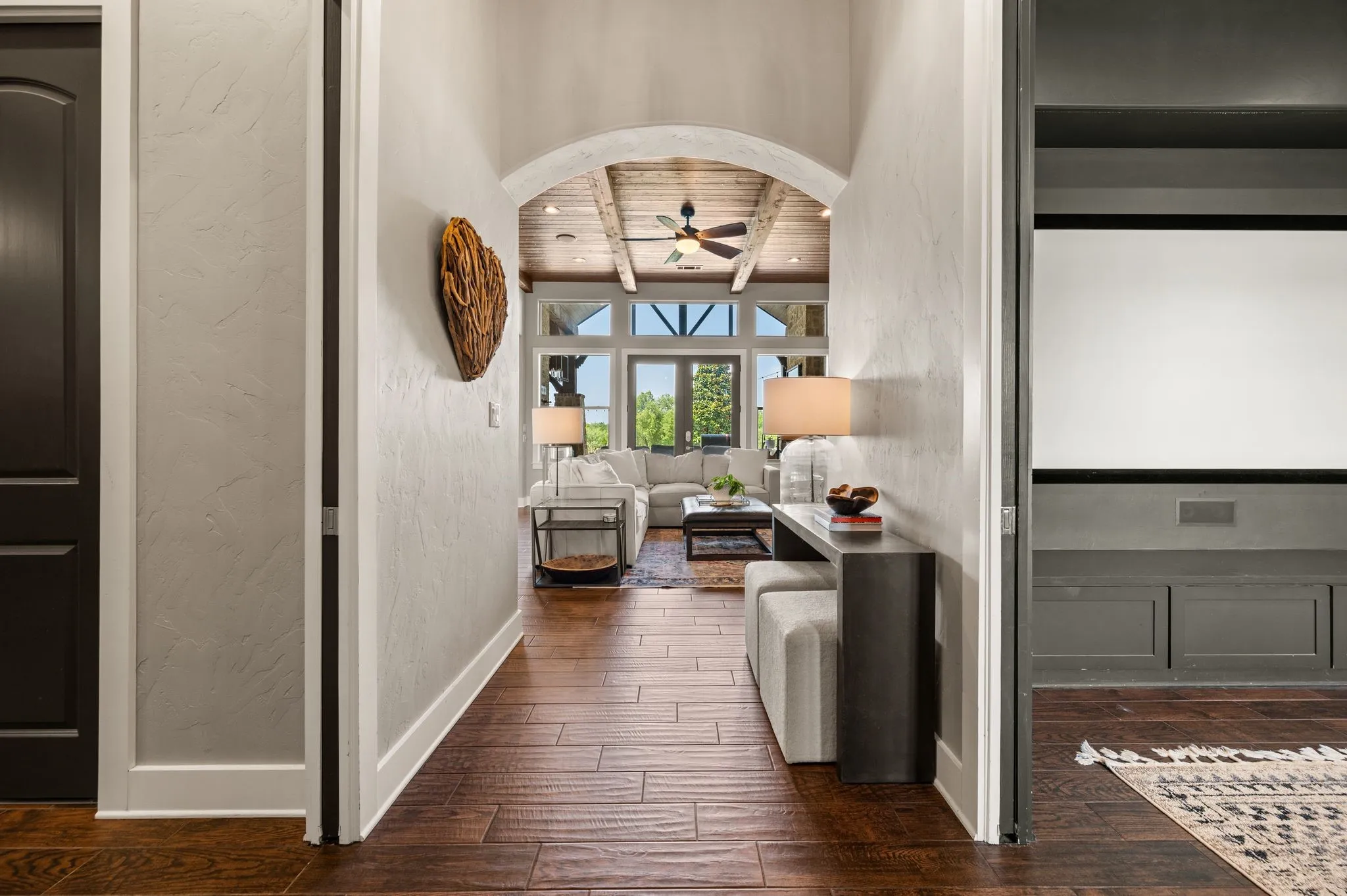 An arched hallway creates an inviting transition into the open living area, framed by rich tile wood -like floors & elevated architectural details.
