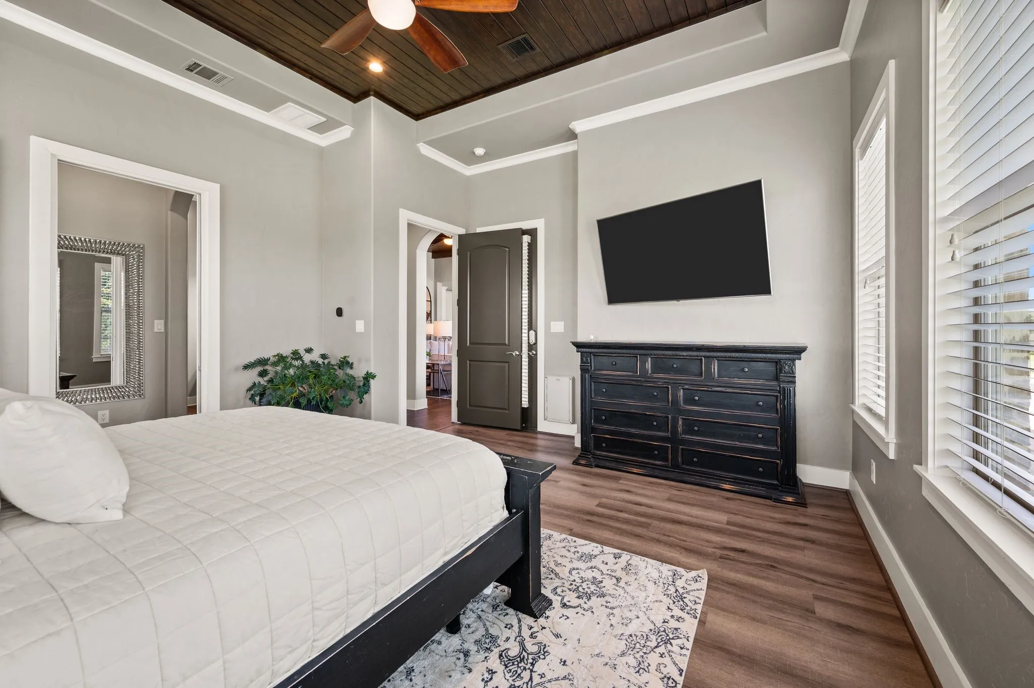 Another view of the primary suite highlights its generous proportions, rich ceiling detail, crown molding & plenty of space for additional furnishings.