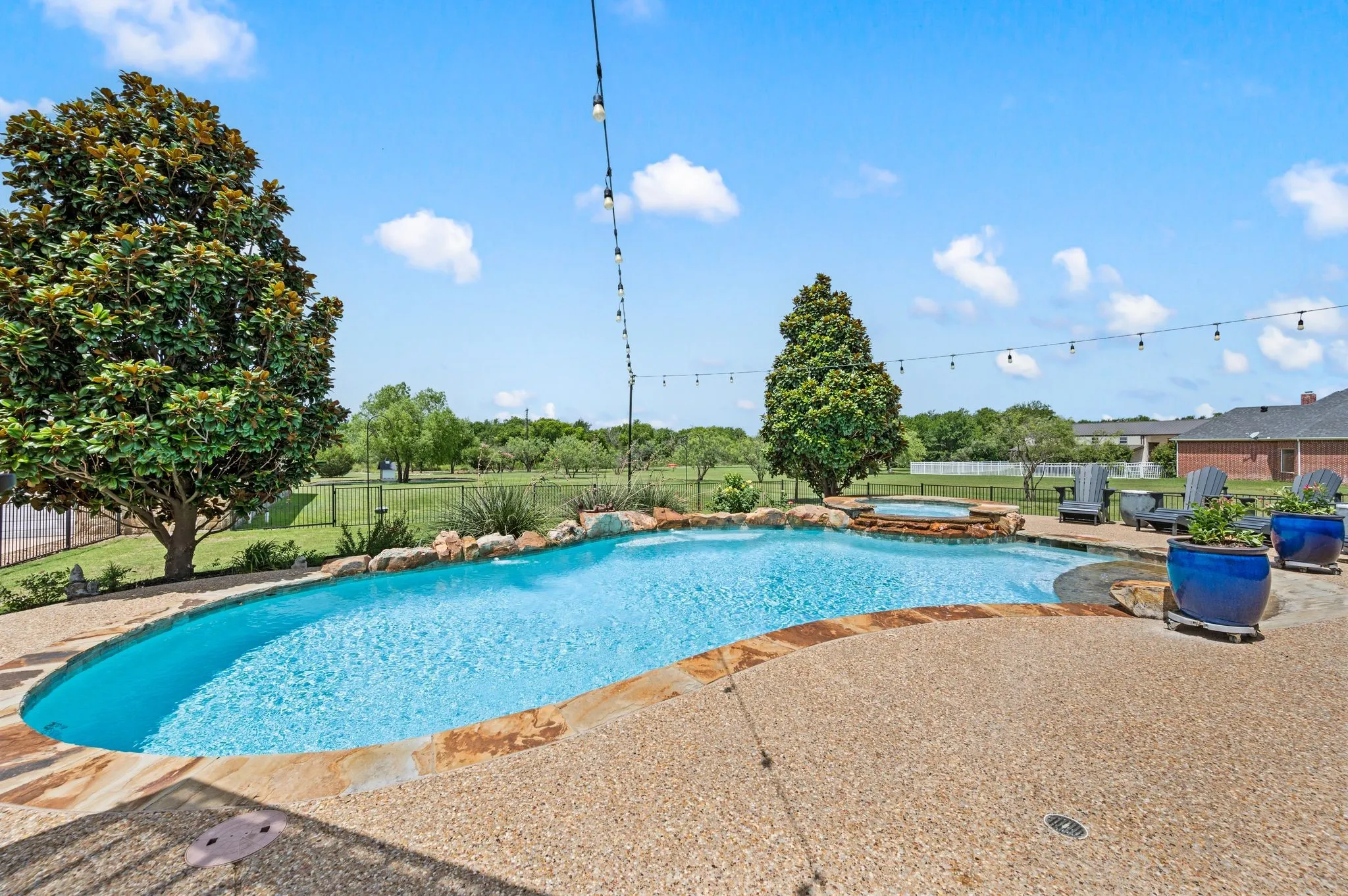 Another view of the expansive pool highlights its free-form design, sun shelf, stone coping & peaceful views across the property.