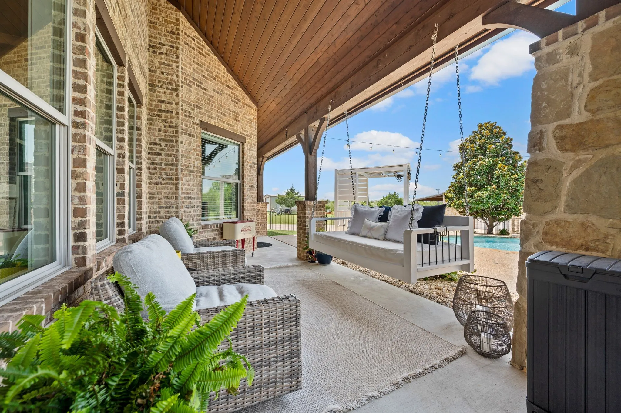 Relax on the expansive covered patio with a charming porch swing & views of the pool and backyard.