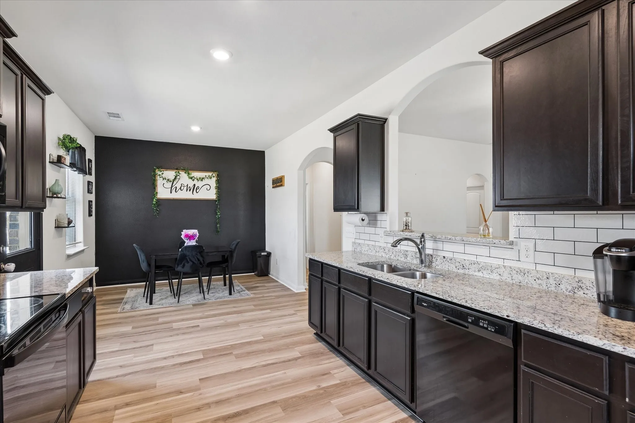 Kitchen featuring dark wood-finish cabinetry, light-toned countertops, and a subway tile backsplash