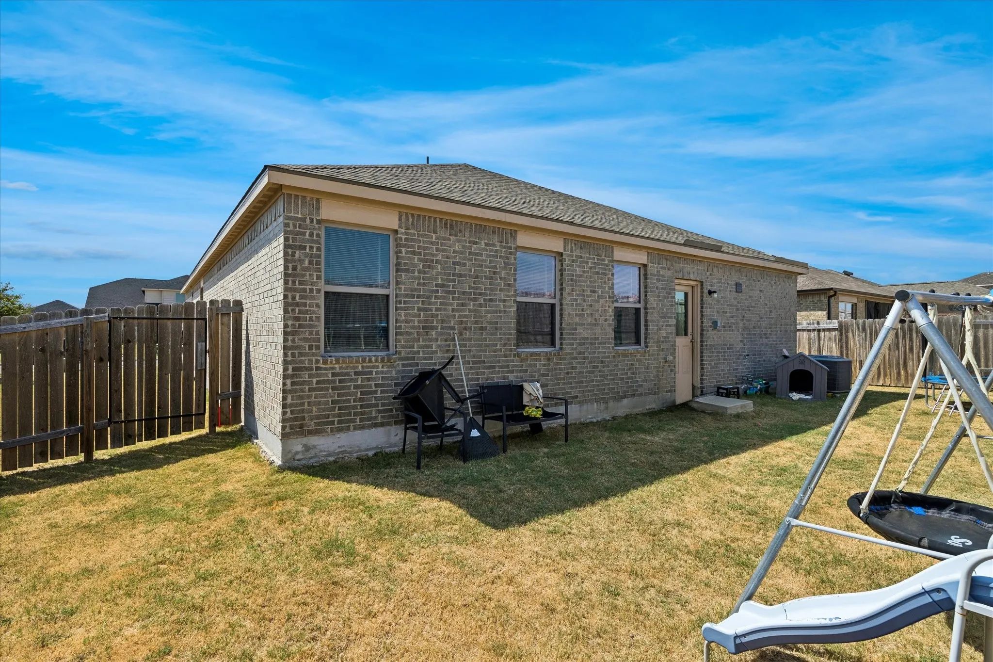Brick exterior with multiple windows and a privacy fence