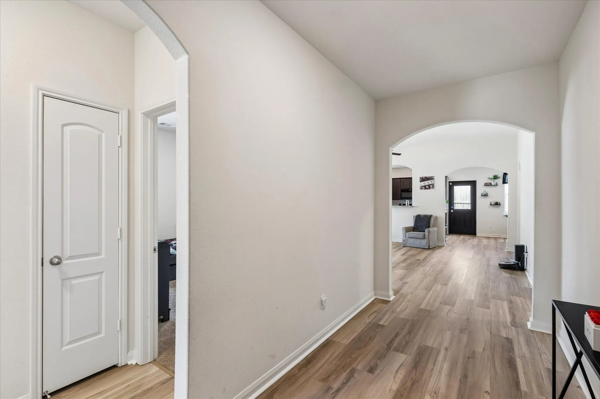 Archway entry with wood-finish flooring, white paneled doors, and light-toned walls