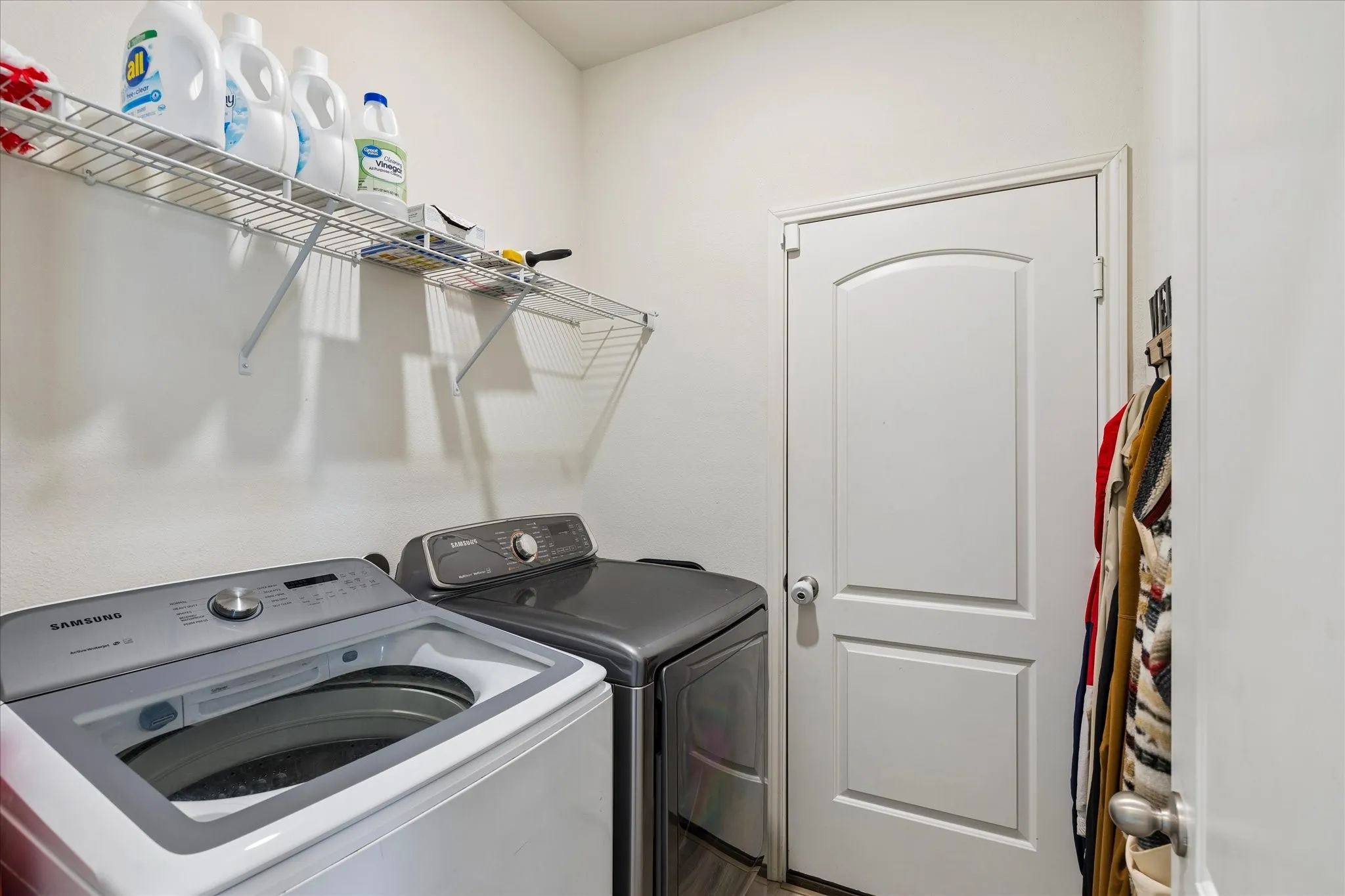 Laundry area featuring an arched panel door and wall-mounted wire shelving