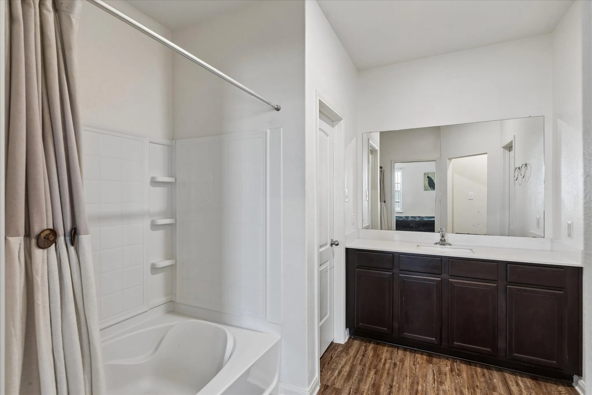 Dark wood-finish vanity with an integrated sink, white countertop, and a large wall-mounted mirror