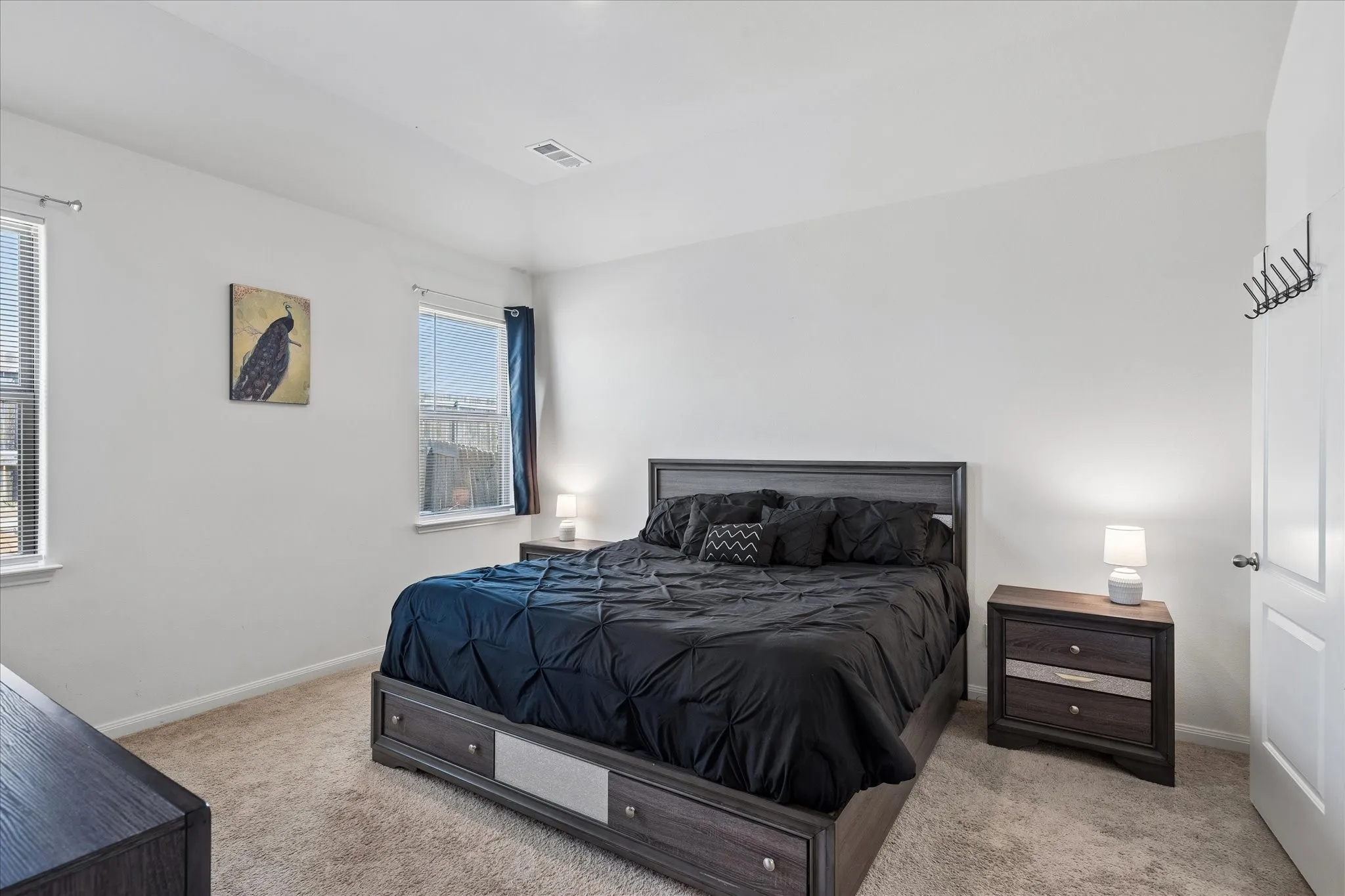 Recessed ceiling, neutral wall paint, carpet flooring, two windows with blinds, white paneled door