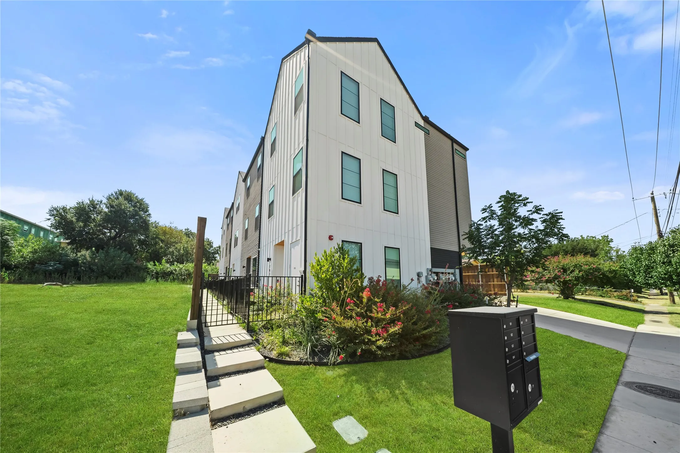 Modern multi-story residence featuring a clean geometric facade with board-and-batten siding, horizontal window bands across three levels, and a peaked roofline