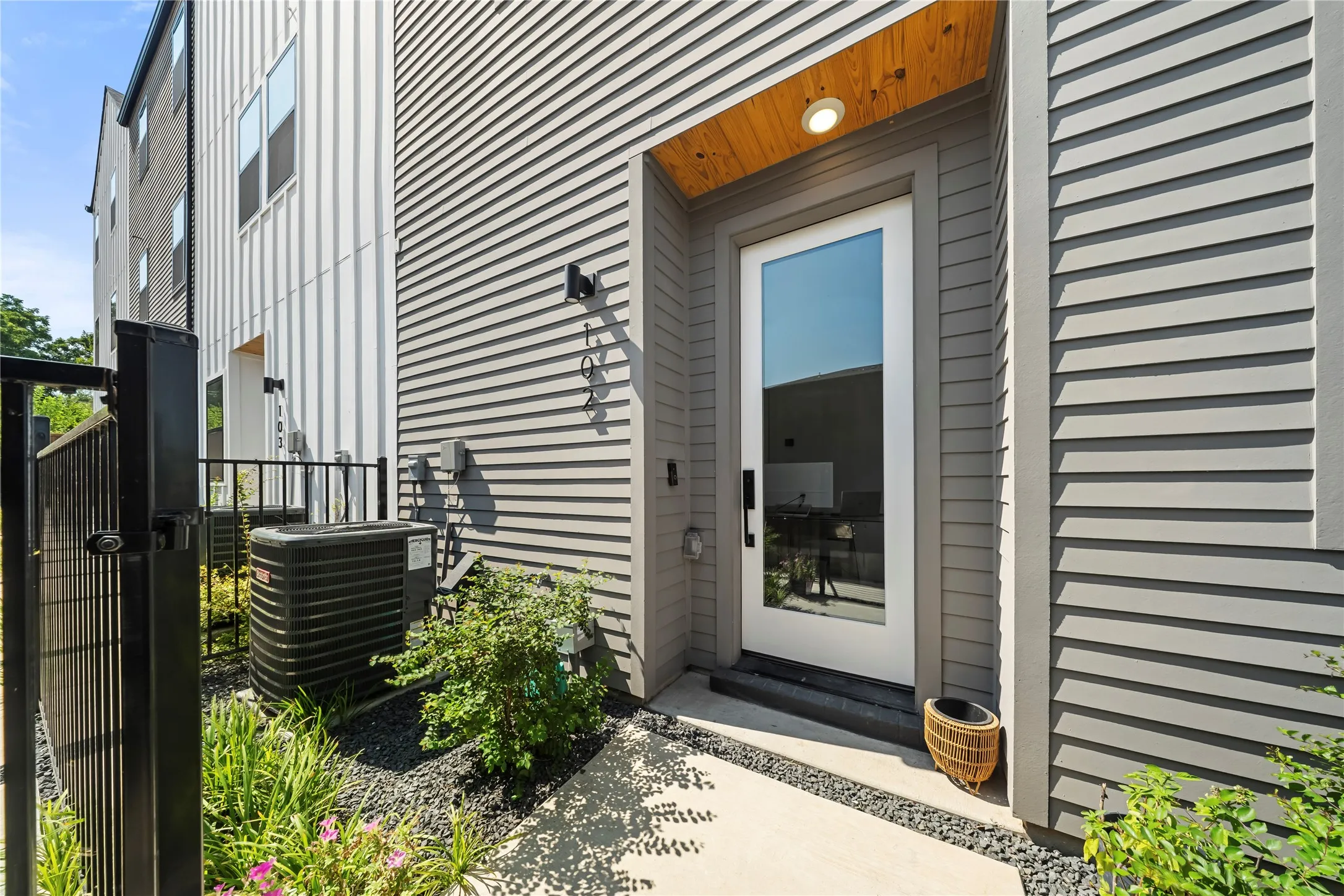 Modern exterior featuring horizontal siding, a full-lite entry door, and an overhead wood-finish accent