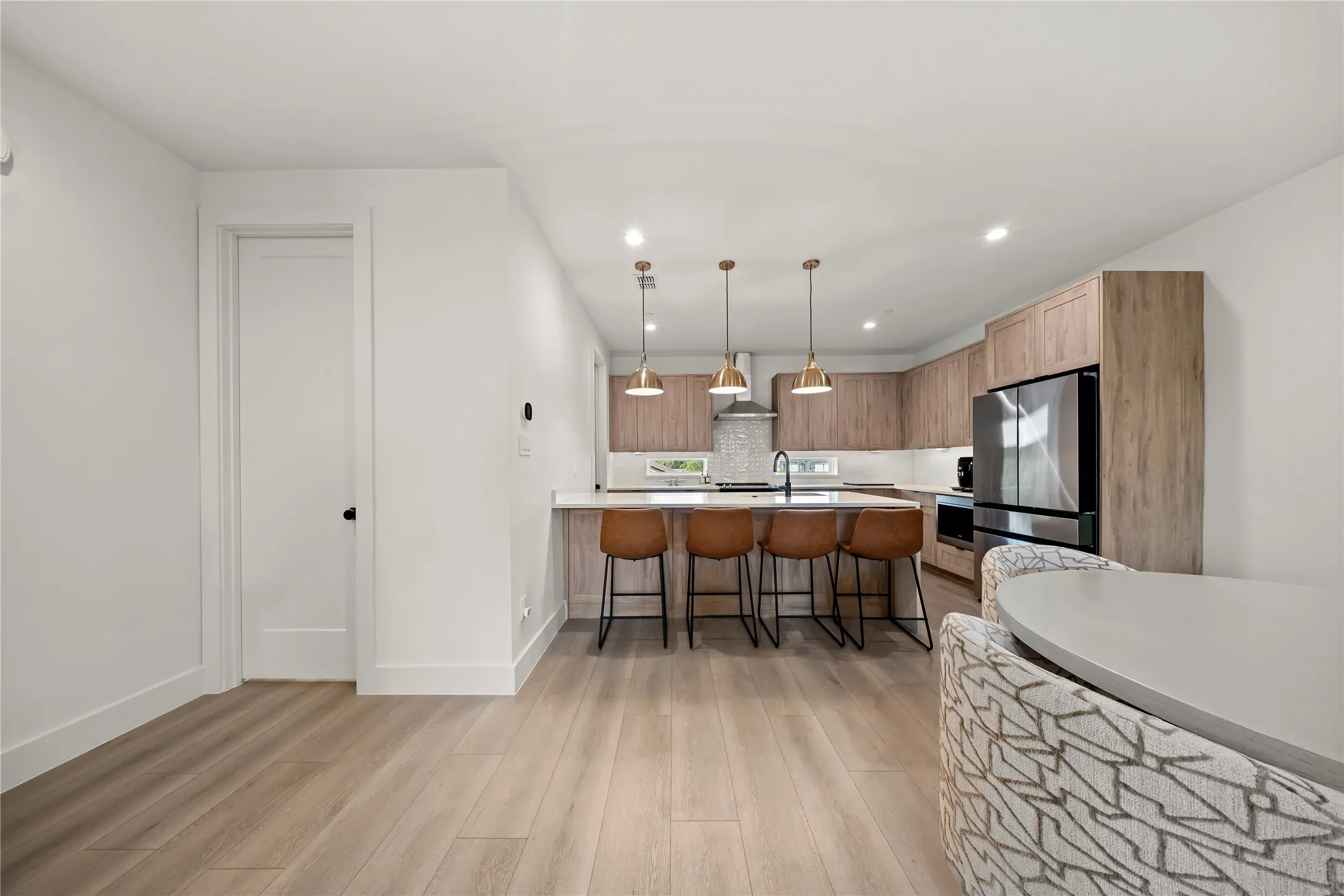 Open-concept kitchen featuring wood-finish cabinetry, stainless steel appliances, and a breakfast bar with pendant lighting