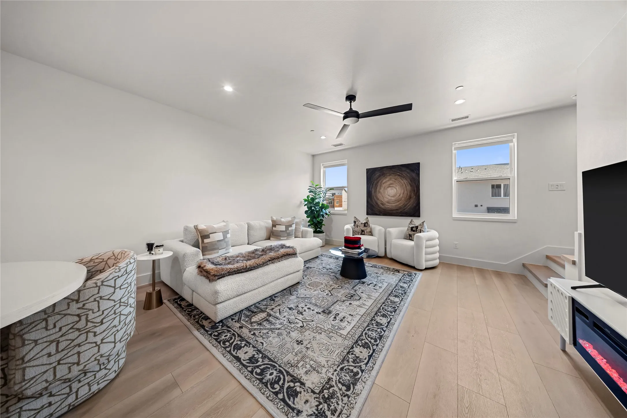 Open-concept living space featuring light wood-finish flooring, recessed lighting, and a modern ceiling fan