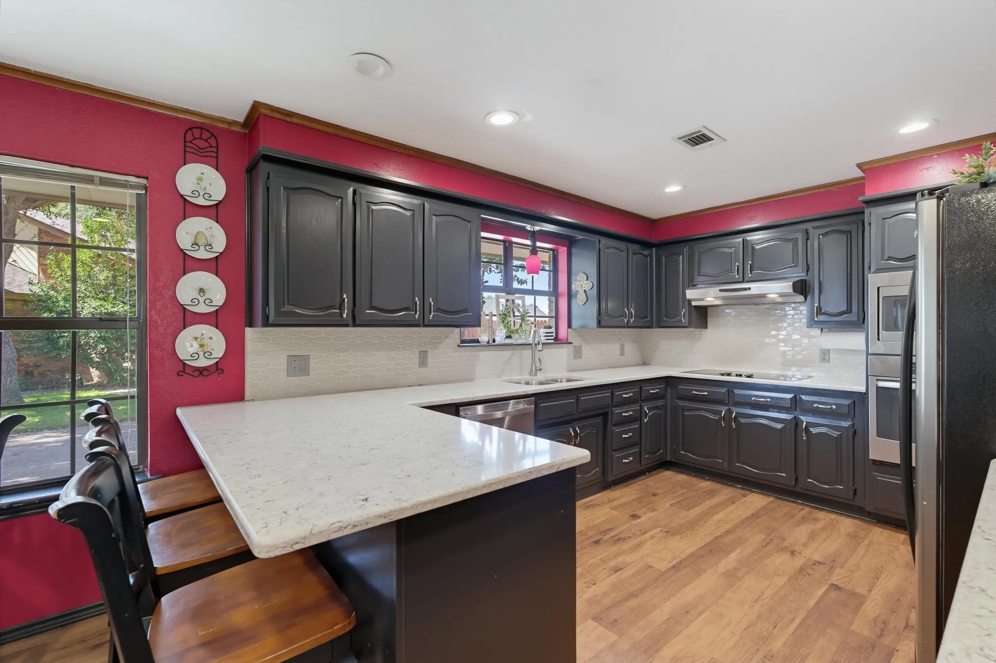 Chef's kitchen featuring dark cabinetry, white quartz countertops, stainless steel appliances, subway tile backsplash, and a large center island with seating