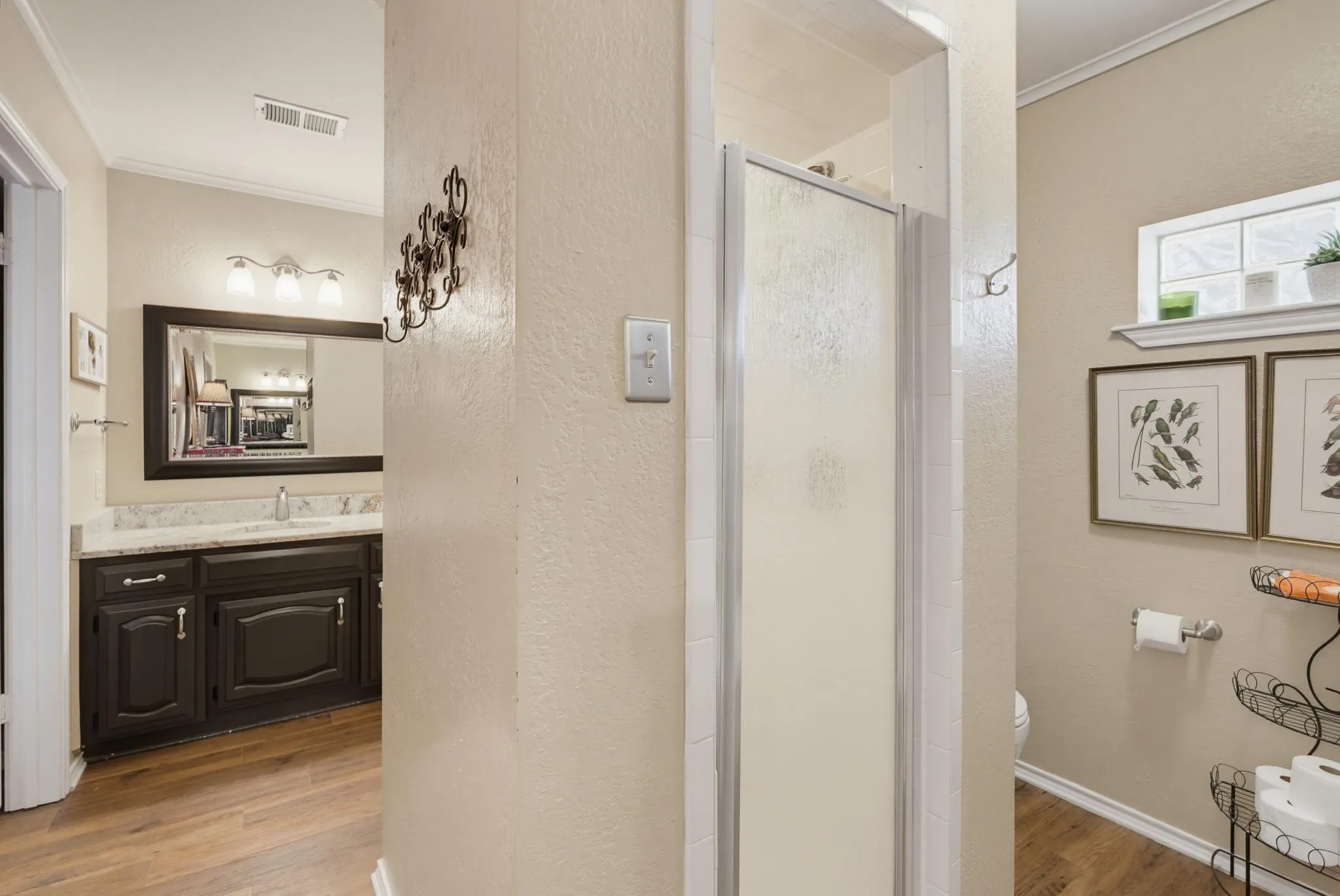 Bathroom featuring a dark wood finish vanity with a rectangular basin sink, a stone-finish countertop, and a framed mirror