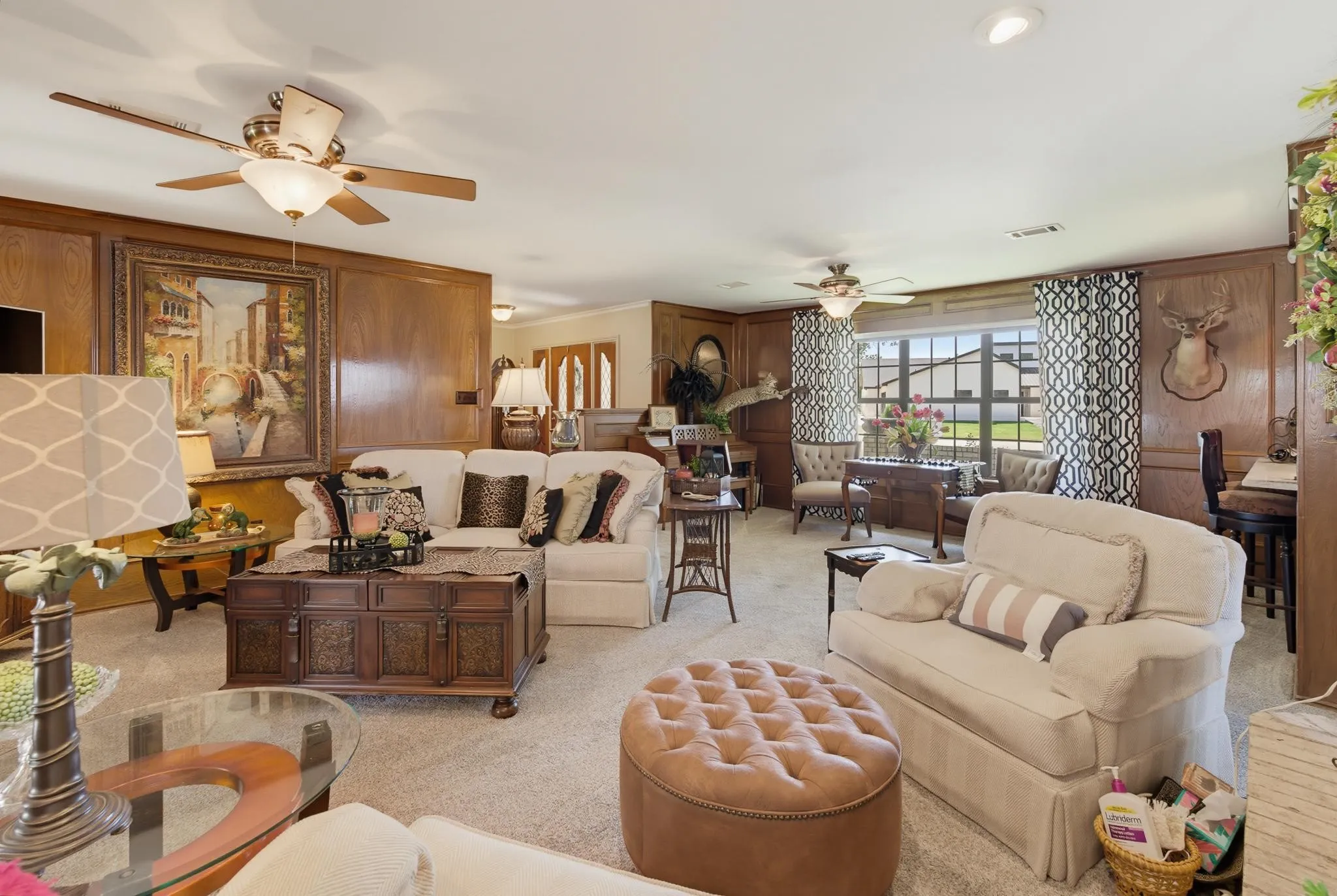 Wood paneling, recessed lighting, ceiling fans, multiple windows, and light-toned carpet