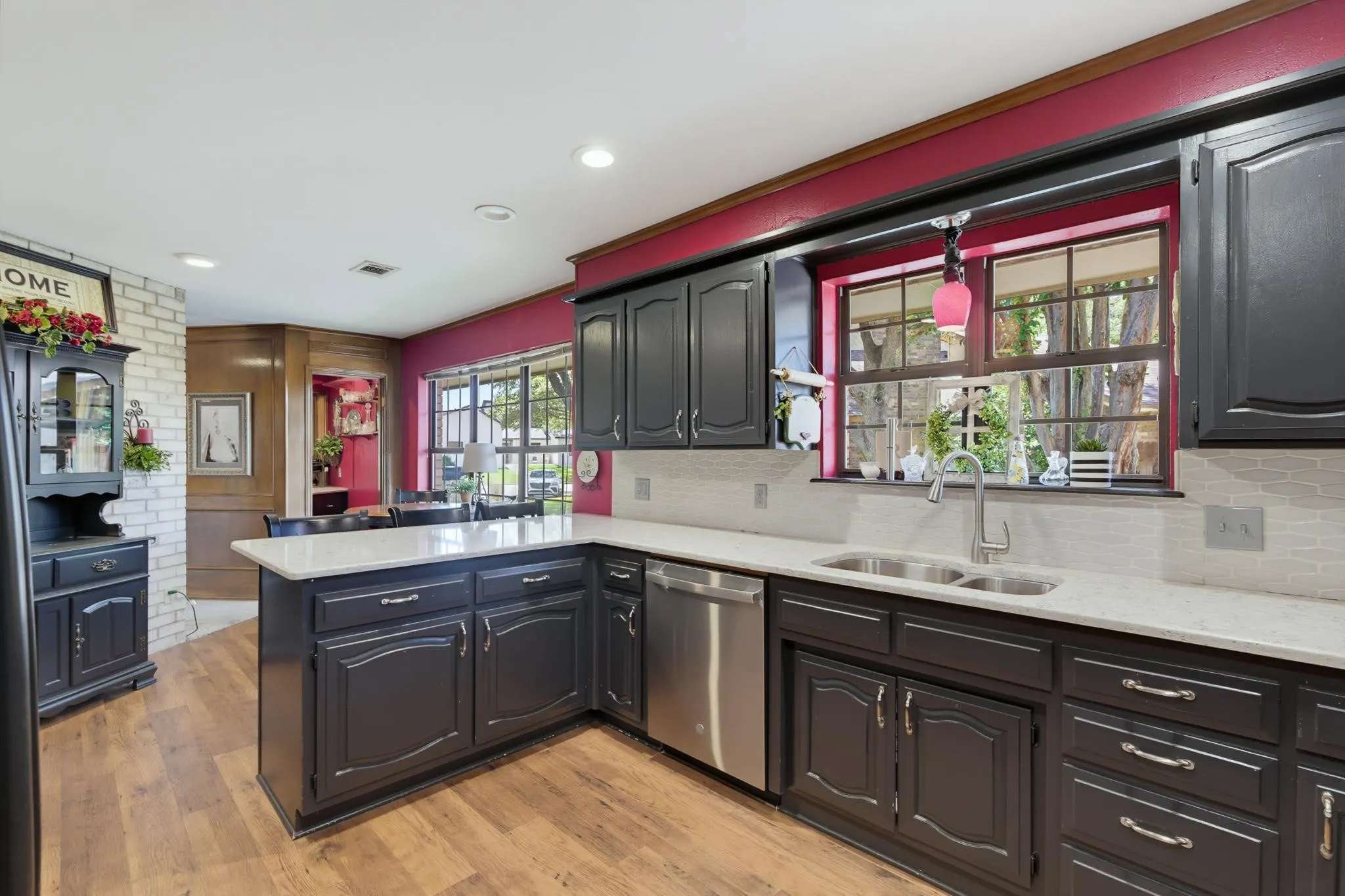 Kitchen featuring dark cabinetry, light-toned countertops, a stainless steel sink, and wood-finish flooring