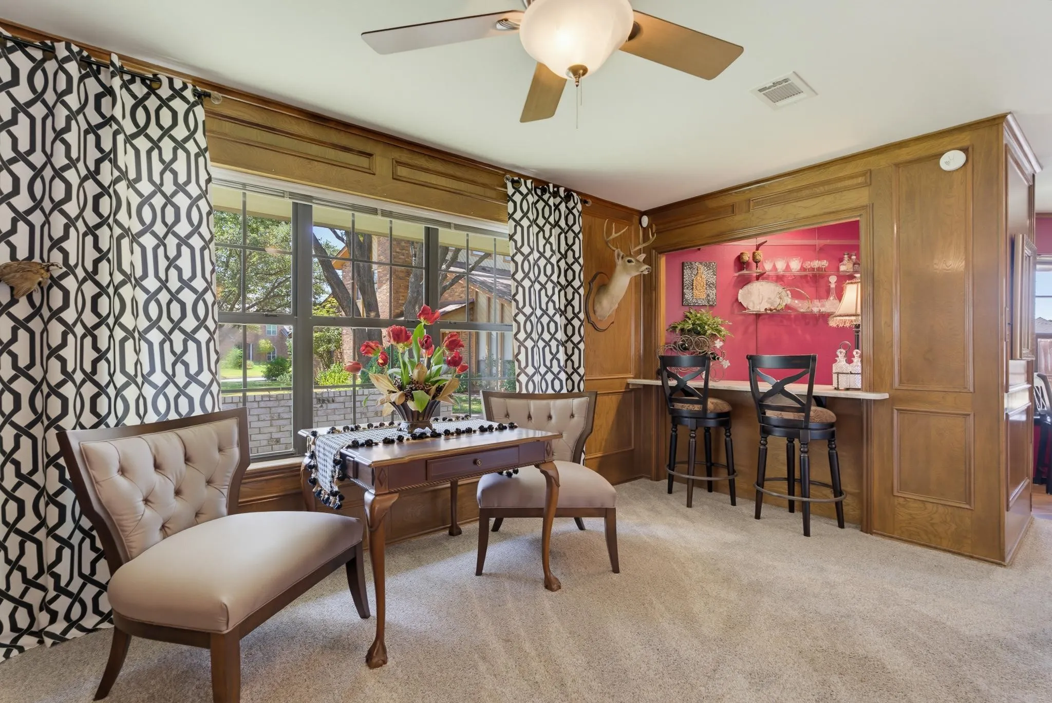 Built-in bar with counter seating, wood paneling, and a ceiling fan