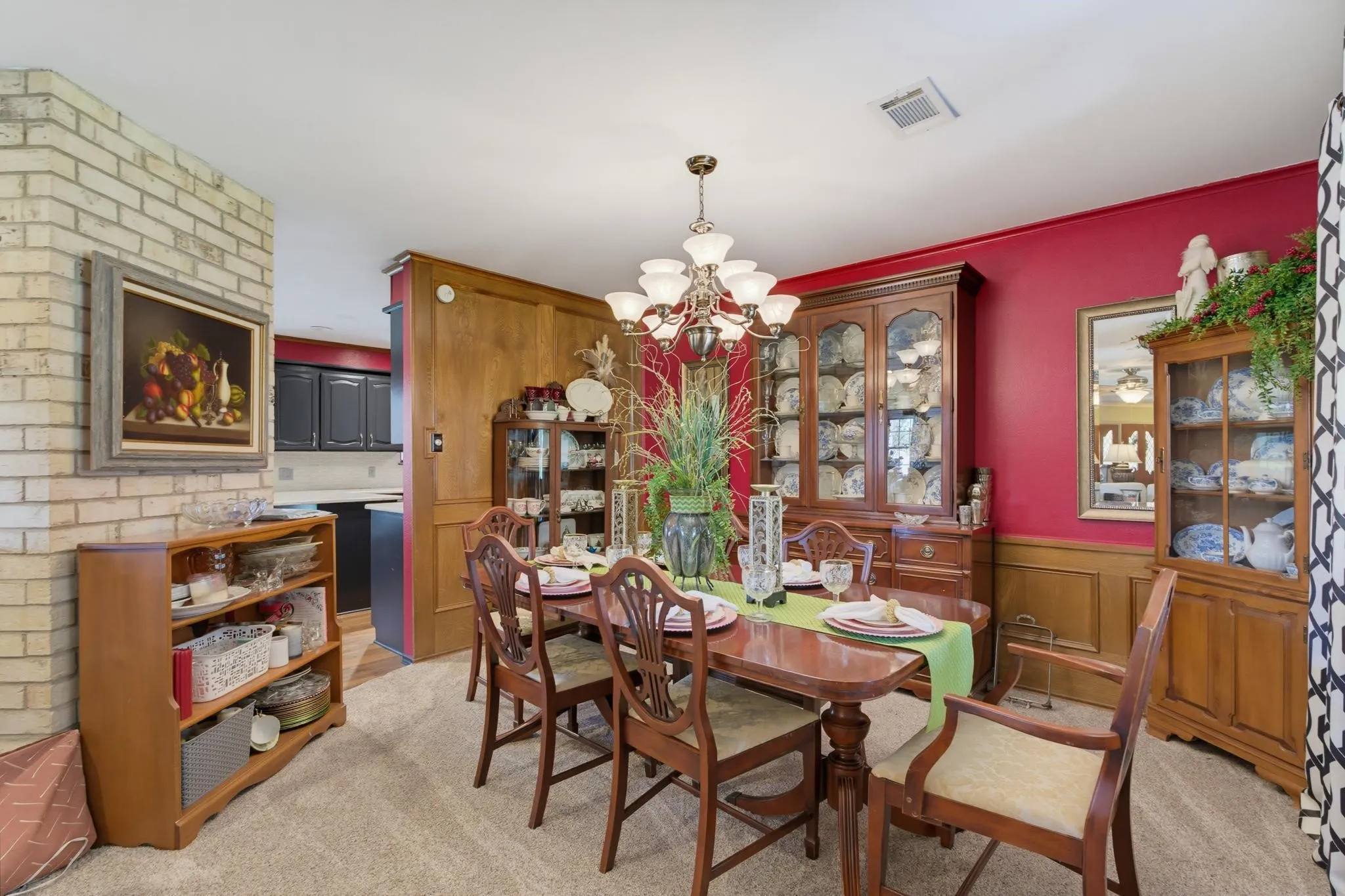 Brick accent wall with a wood-paneled wall, overhead chandelier, and built-in display cabinetry