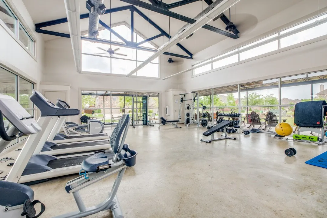 Vaulted ceiling with exposed structural beams, clerestory windows, full-height glass panels, and concrete flooring
