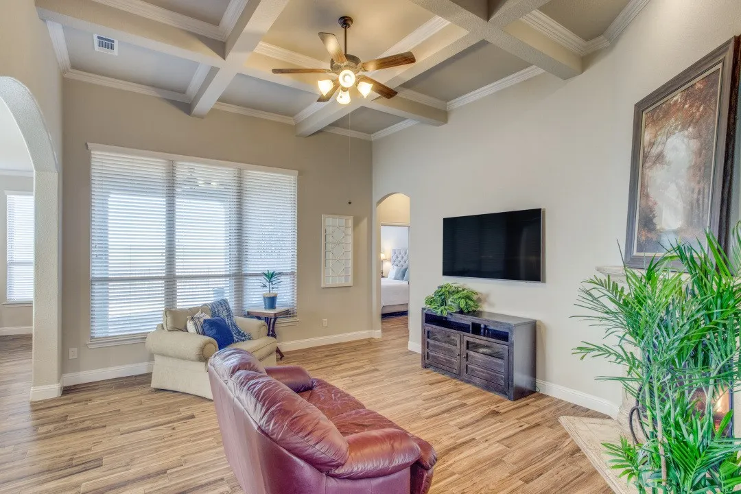 Coffered ceiling with a ceiling fan, large windows, wood-finish flooring, and arched doorways