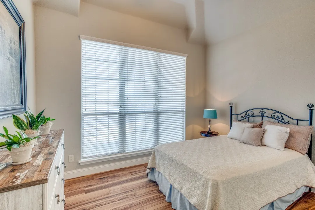 Vaulted ceiling, wood-finish flooring, large window with blinds, light wall color, white trim