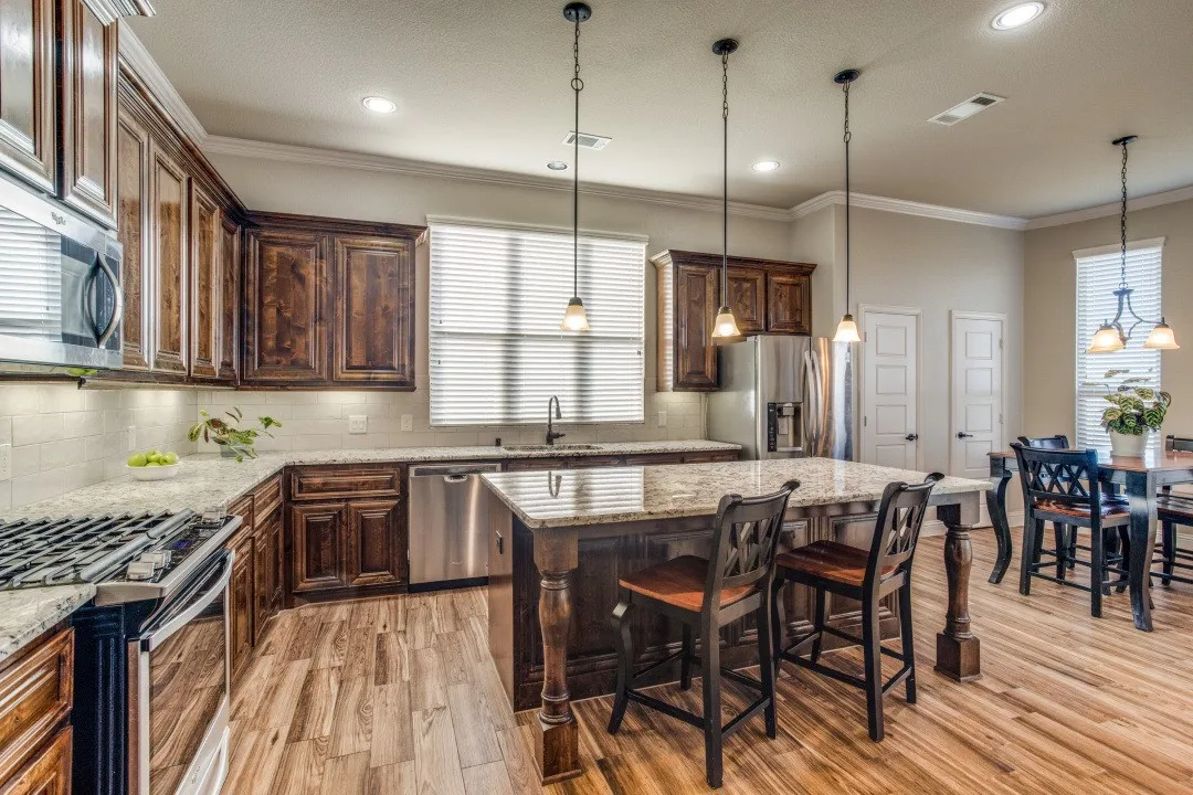 Kitchen featuring wood-finish flooring, dark wood cabinetry, stainless steel appliances, a center island with seating, and granite countertops