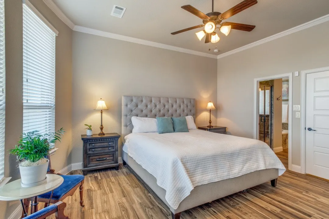 Wood-finish flooring throughout, complemented by a tufted upholstered headboard, and a multi-paneled door