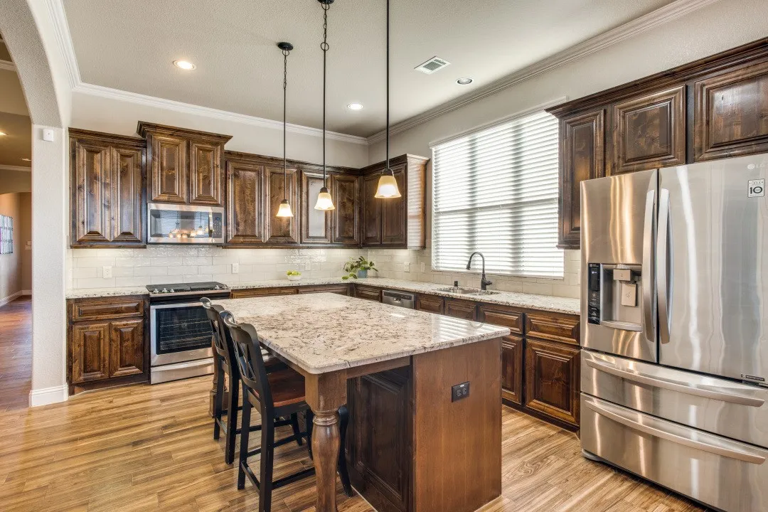 Kitchen featuring wood-finish flooring, dark wood cabinetry, light speckled countertops, a subway tile backsplash, and stainless steel appliances