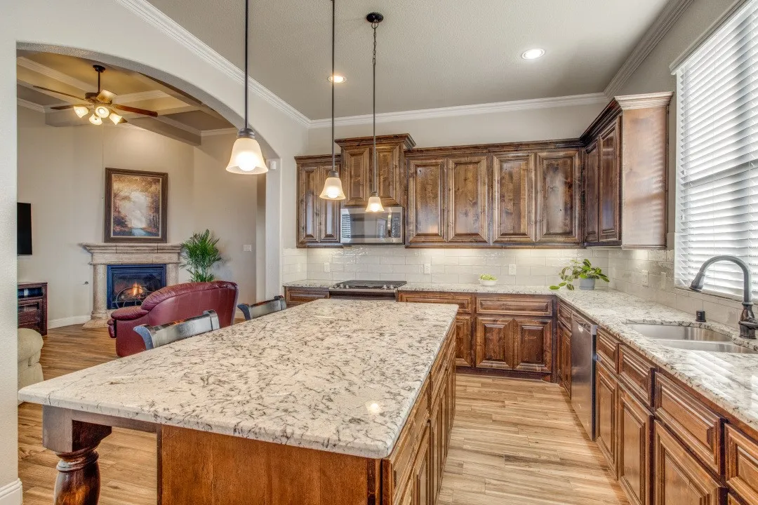 Kitchen featuring wood-finish flooring, wood cabinetry, stone countertops, and a white tile backsplash