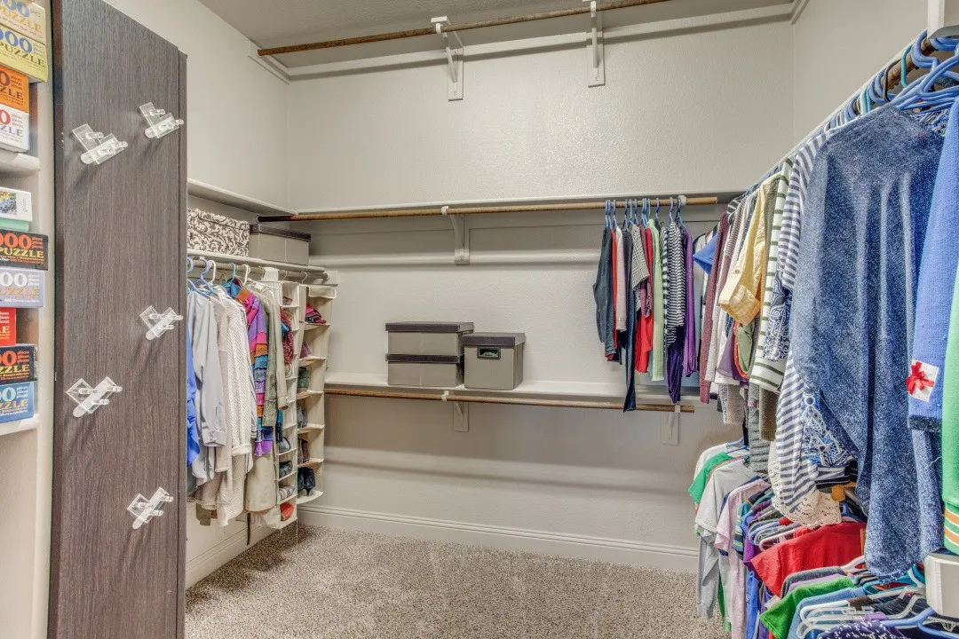 Walk-in closet featuring carpet flooring, built-in shelving, and multiple hanging rods
