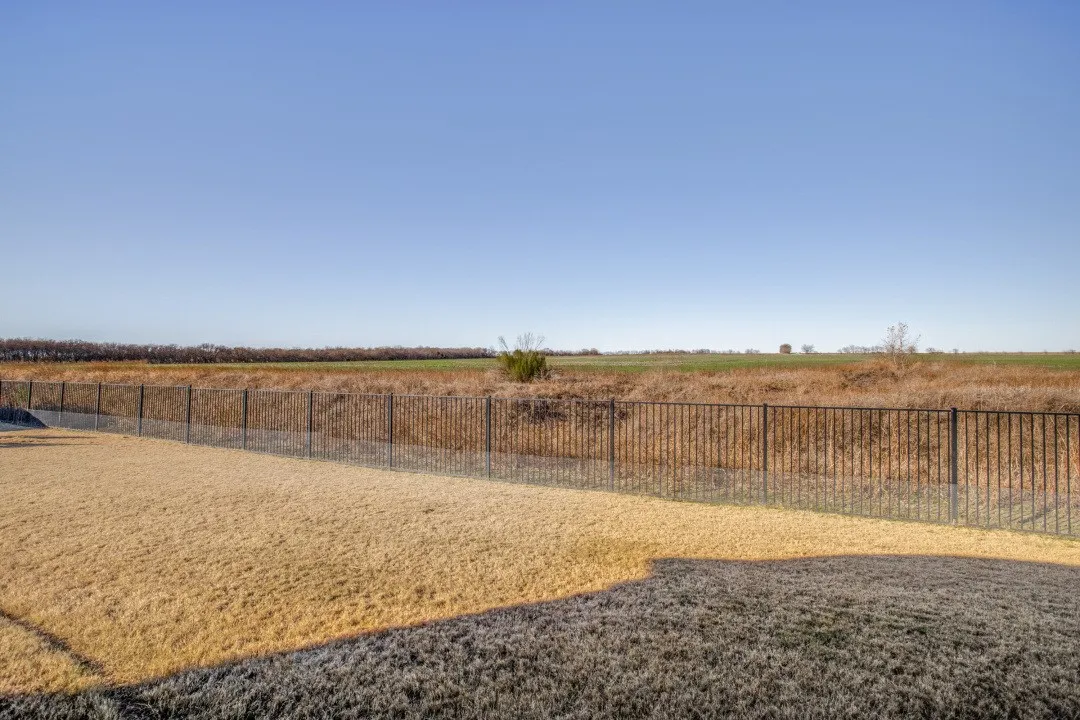 Expansive backyard featuring a wrought iron fence and open field
