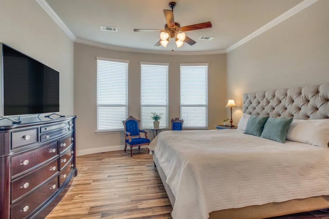 Wood-finish flooring with crown molding and a ceiling fan