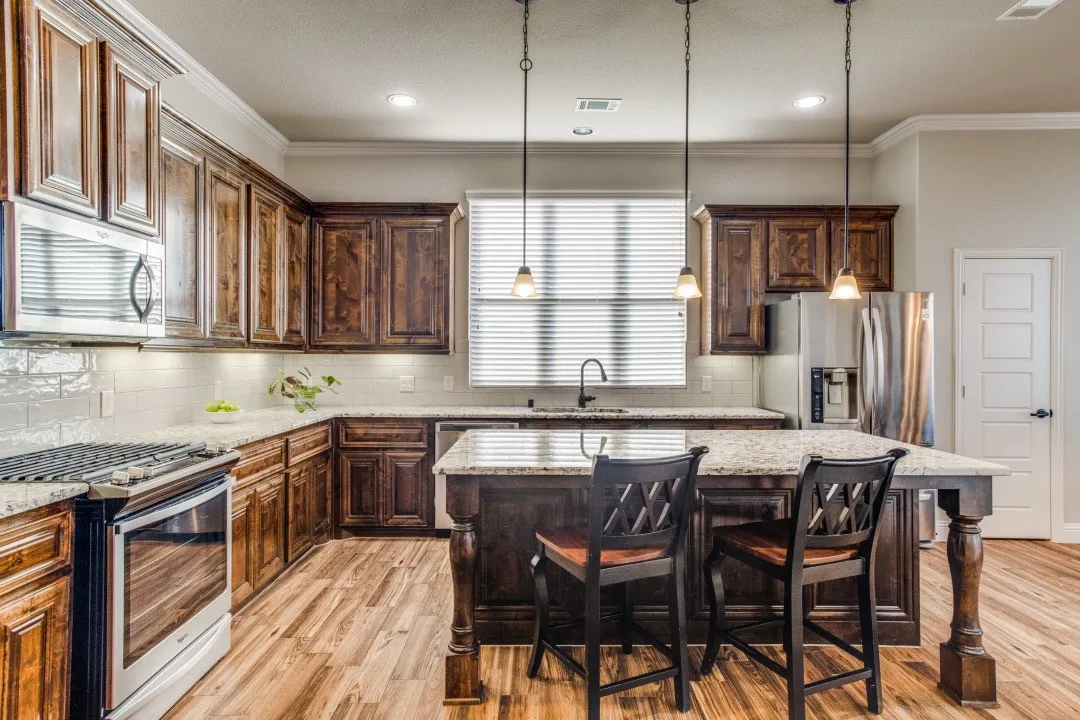 Wood-finish flooring, dark wood cabinetry, stainless steel appliances, light granite countertops, and a white subway tile backsplash