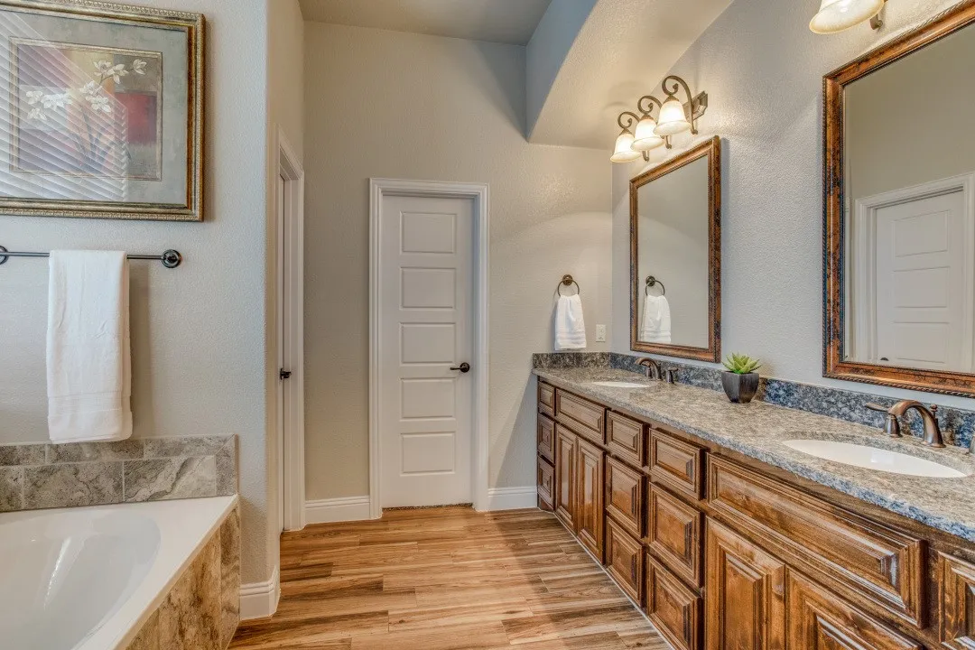 Dual vanity with rich wood cabinetry and undermount sinks, complemented by a stone countertop