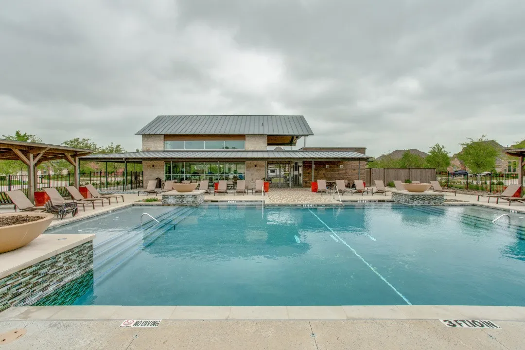 Outdoor swimming pool with integrated fire bowls, expansive concrete decking, and multiple wooden pergolas with metal roofing