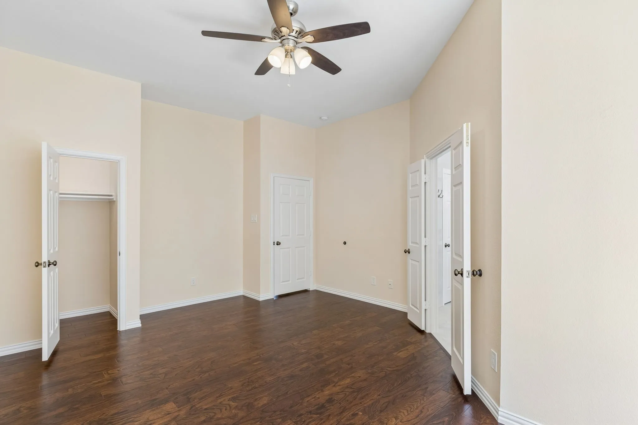 Vaulted ceiling with a ceiling fan, wood-finish flooring, and closet in primary bedroom