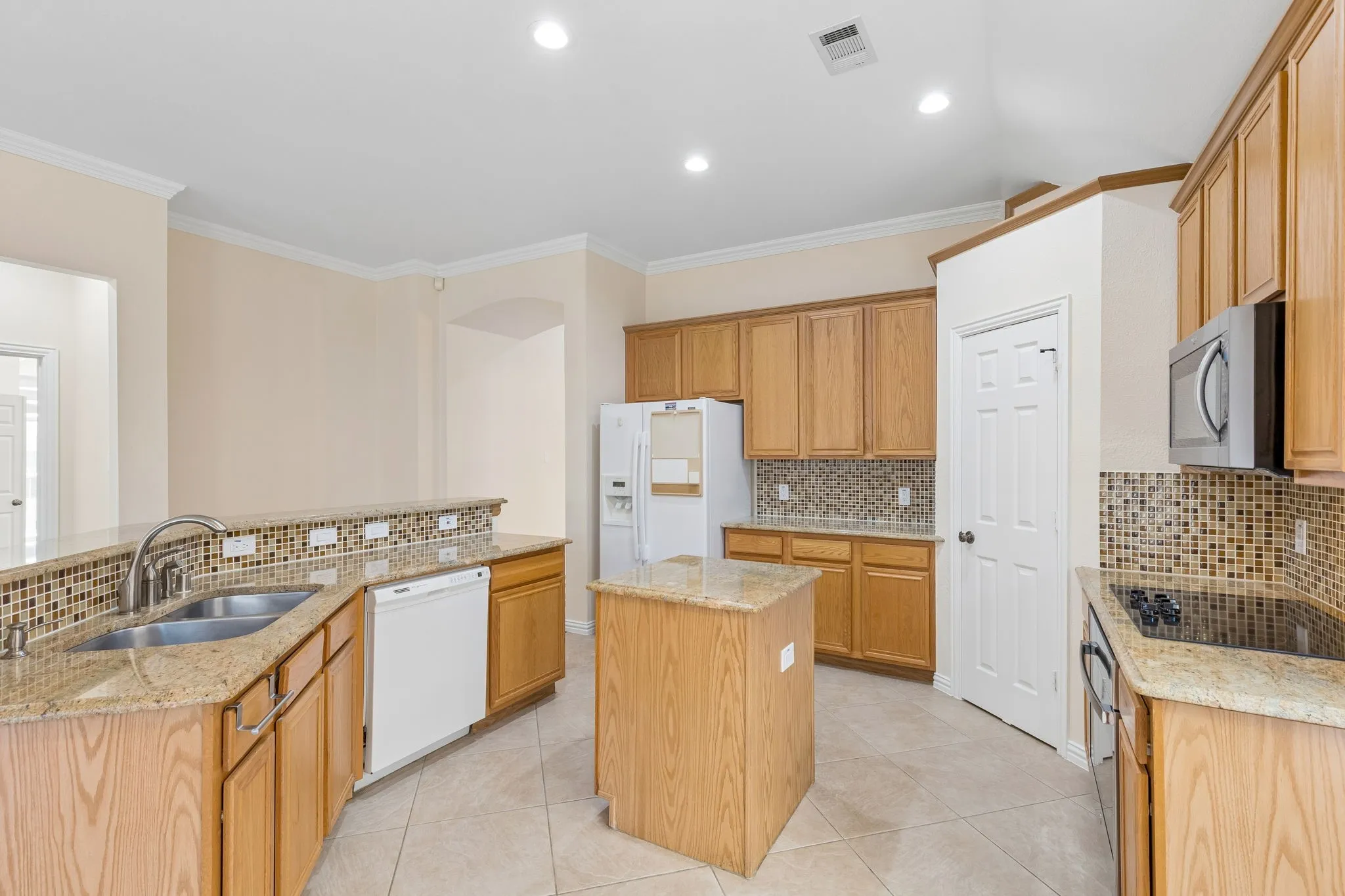 Kitchen featuring wood cabinetry, granite countertops, a mosaic tile backsplash, a center island, and recessed lighting