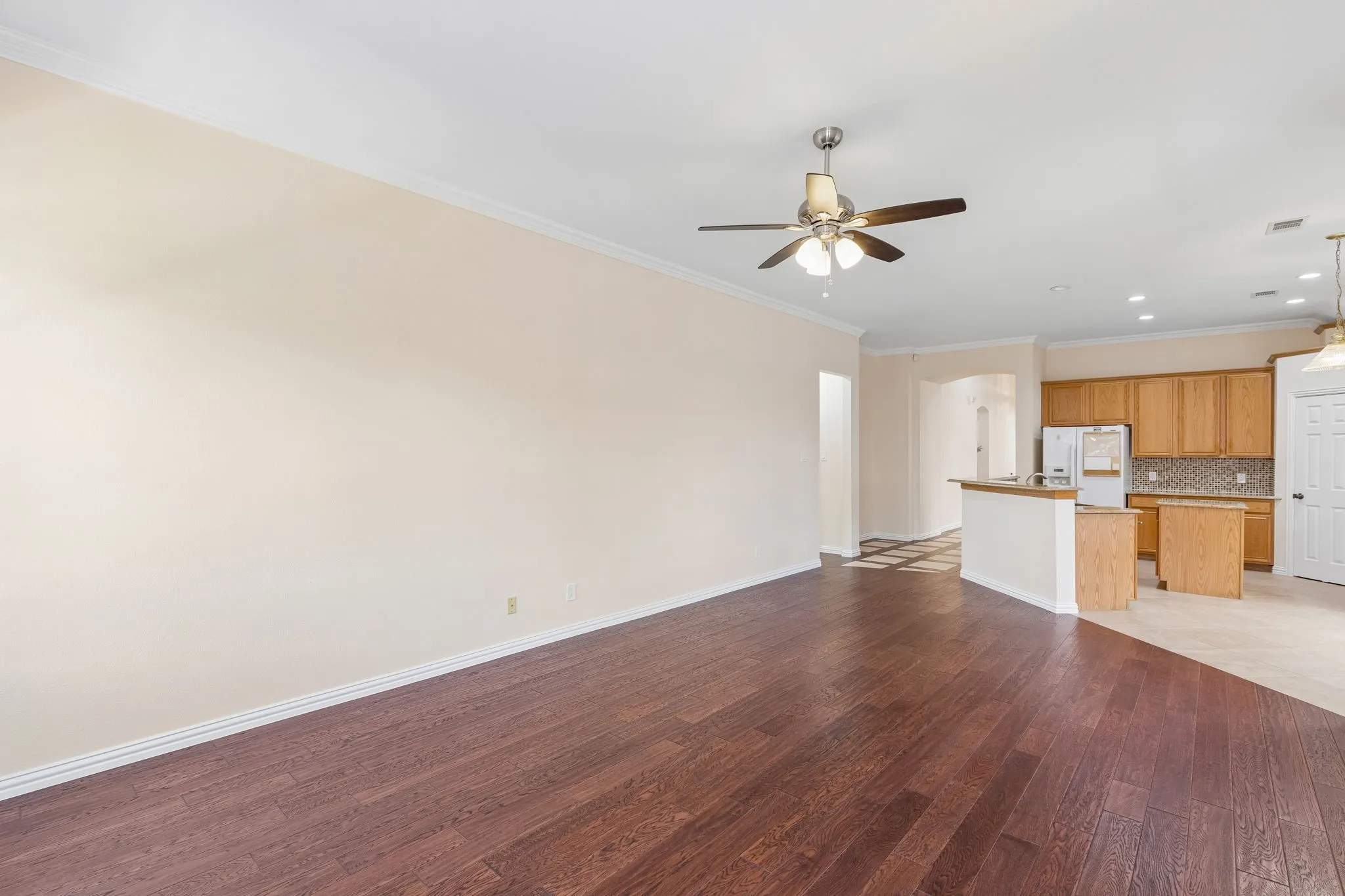 Wood-finish flooring, crown molding, and a ceiling fan with integrated lighting