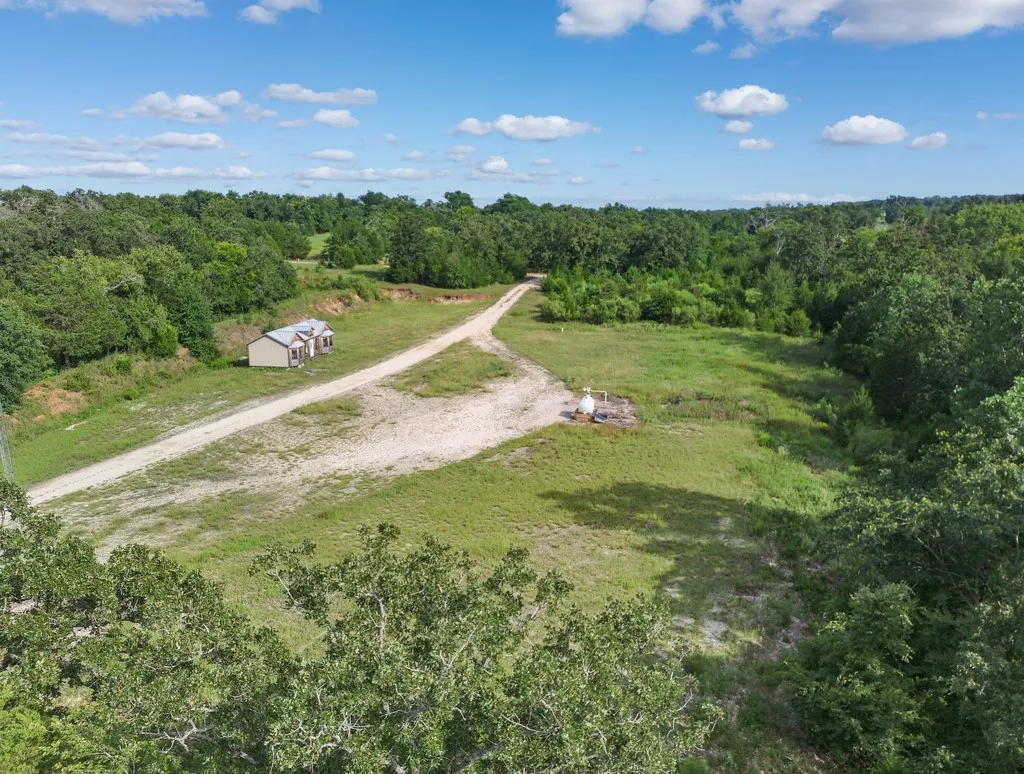 Aerial view of property and surrounding area featuring rural landscape and a forest