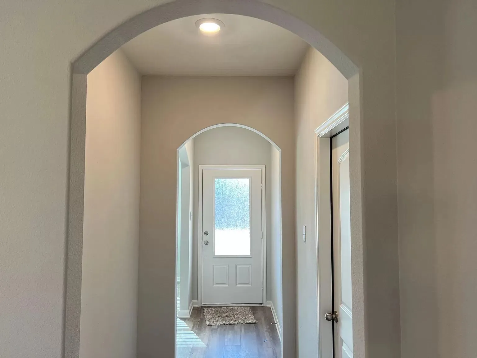 Archway entry with recessed lighting, wood-finish flooring, and white paneled doors