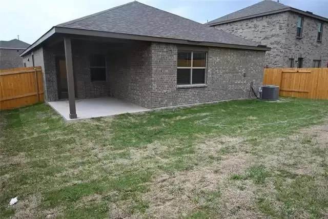 Brick exterior residence featuring a covered patio, concrete slab, and wood privacy fencing