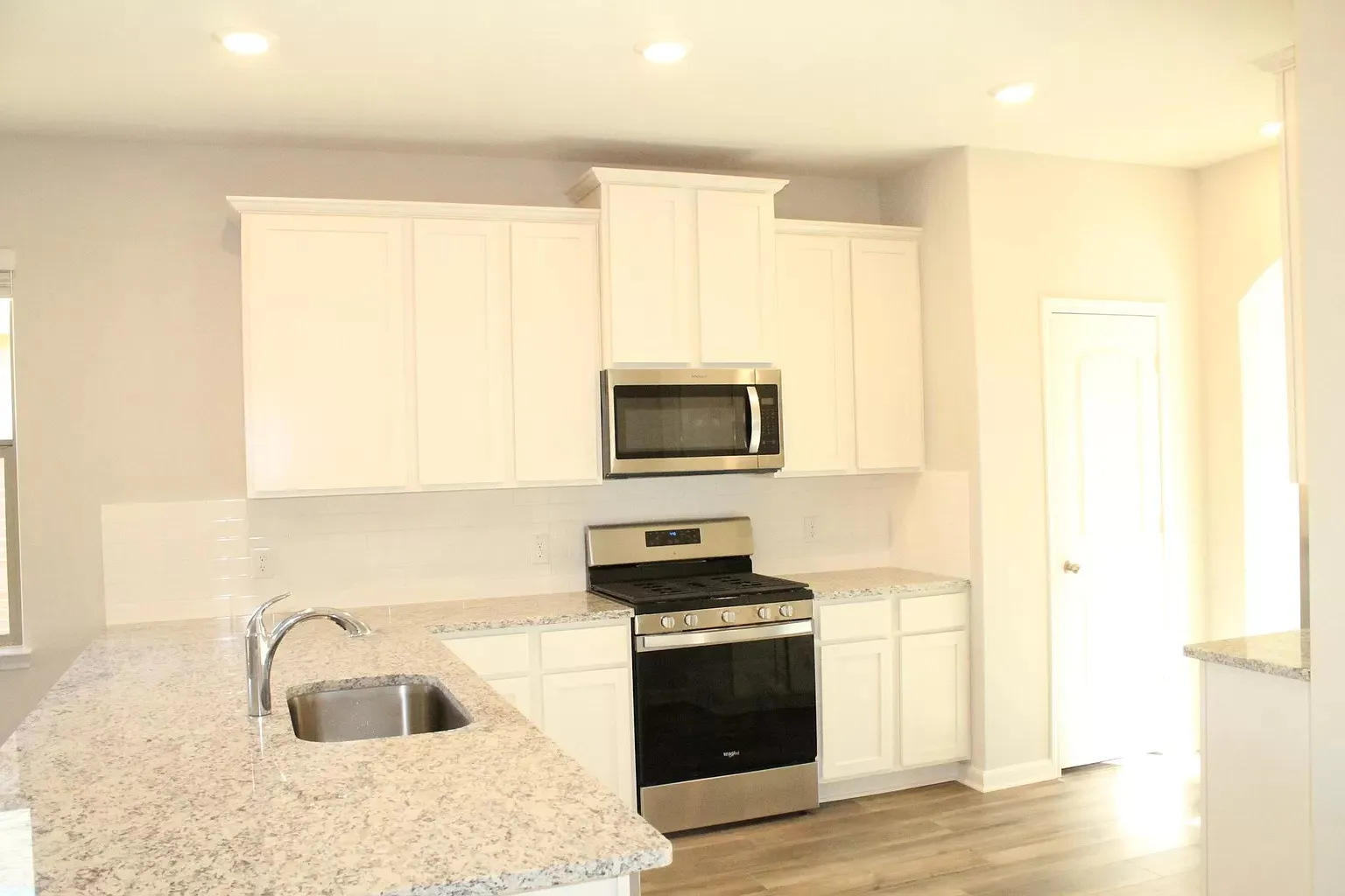 Kitchen featuring white cabinetry, stainless steel appliances, speckled countertops, and a single-basin sink with a gooseneck faucet